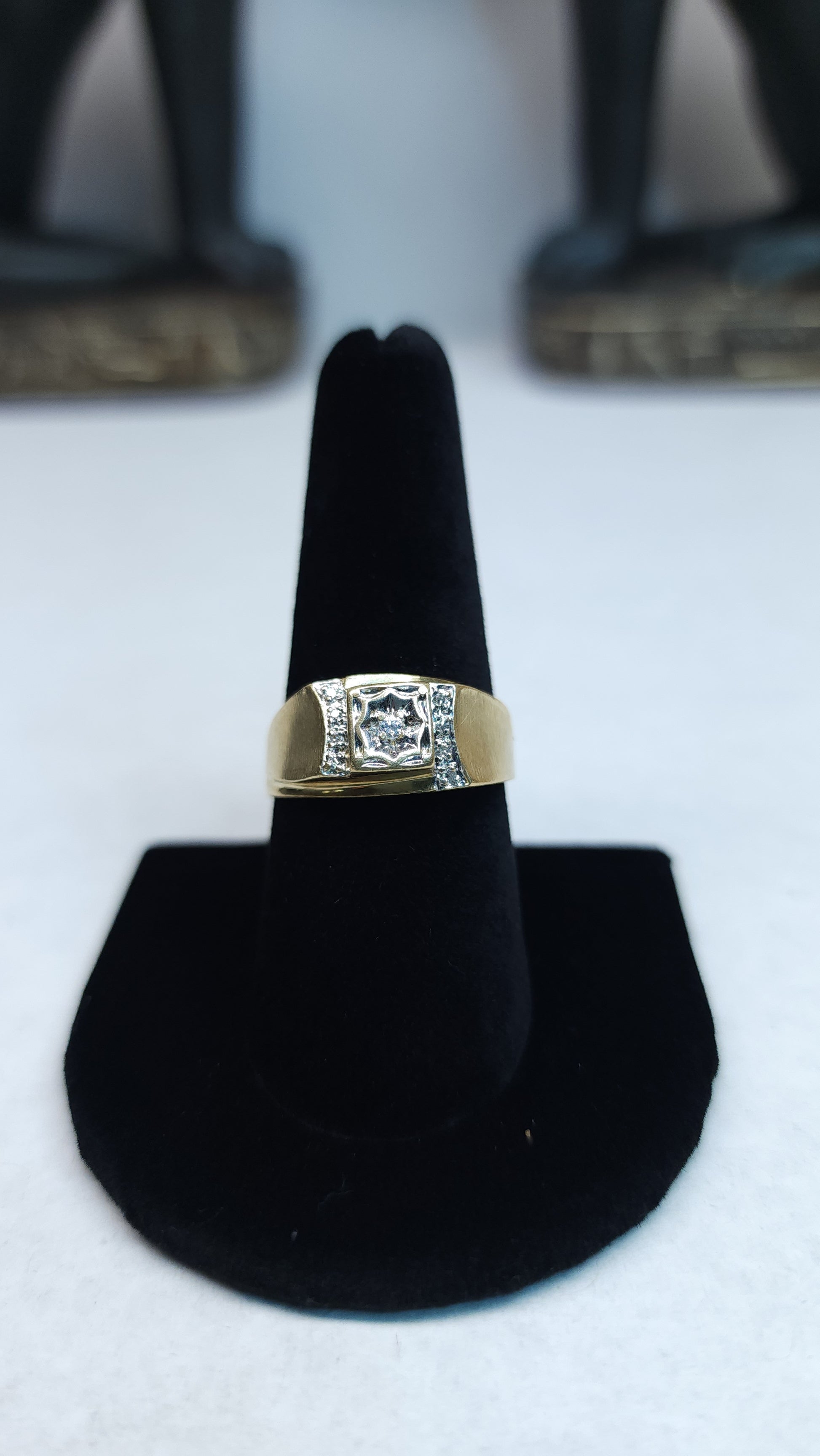 This bold 10k ring is mounted with small micro diamonds to help the peak of the design to shine. The center stone is showcased in an impressive illusion set to give it a big stone look. This piece has some signs of wear. Price is reflective