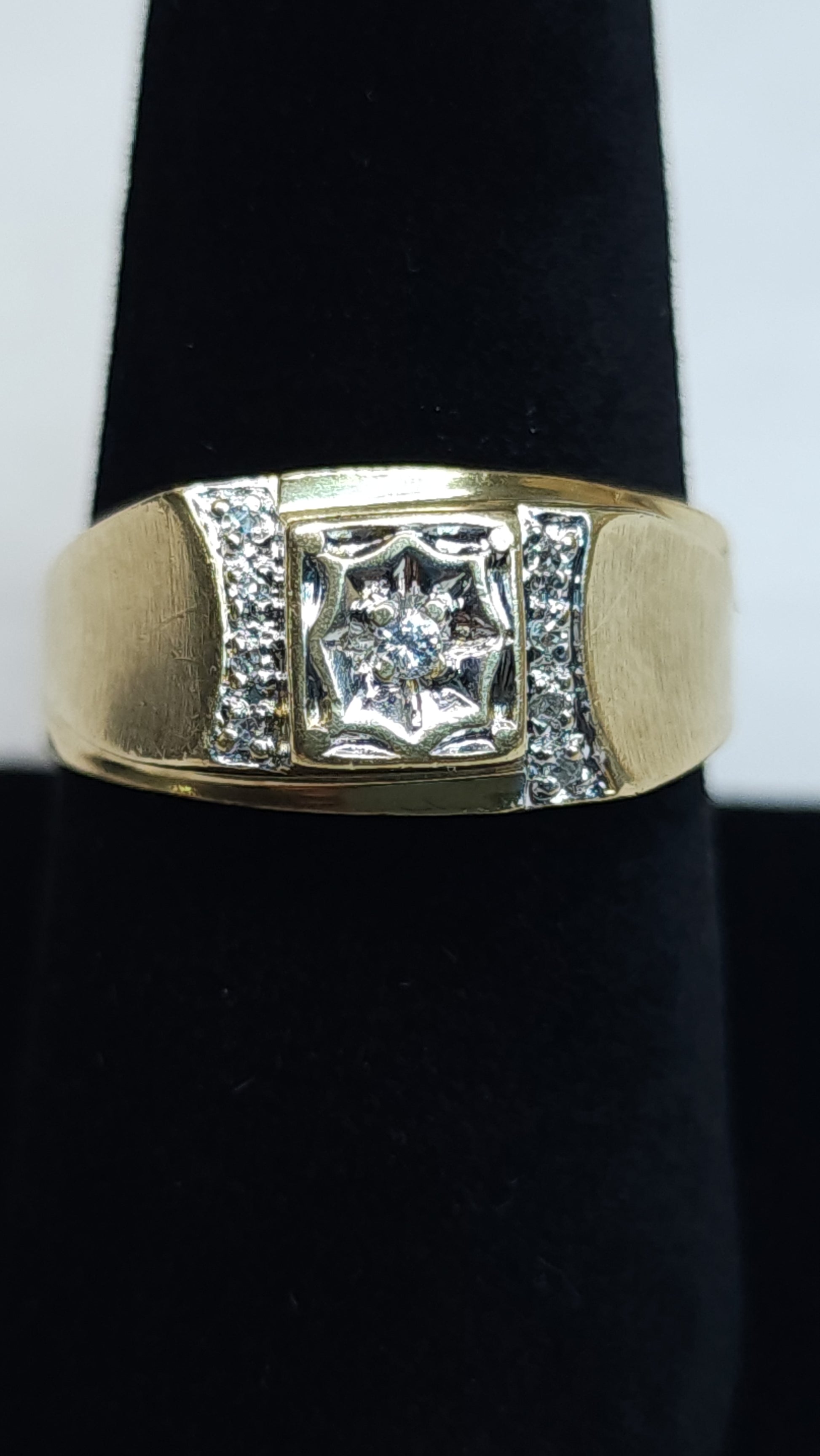 This bold 10k ring is mounted with small micro diamonds to help the peak of the design to shine. The center stone is showcased in an impressive illusion set to give it a big stone look. This piece has some signs of wear. Price is reflective